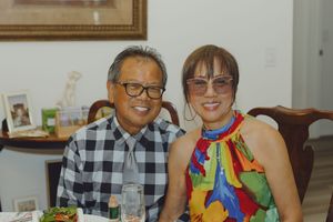 Smiling elderly Asian couple sitting together at a dining table during a celebration.
