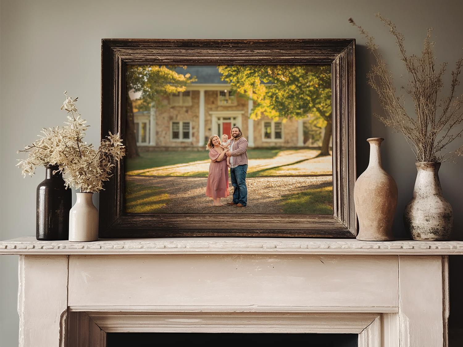 Framed photo of a couple embracing outdoors displayed on a white fireplace mantel with decorative vases.