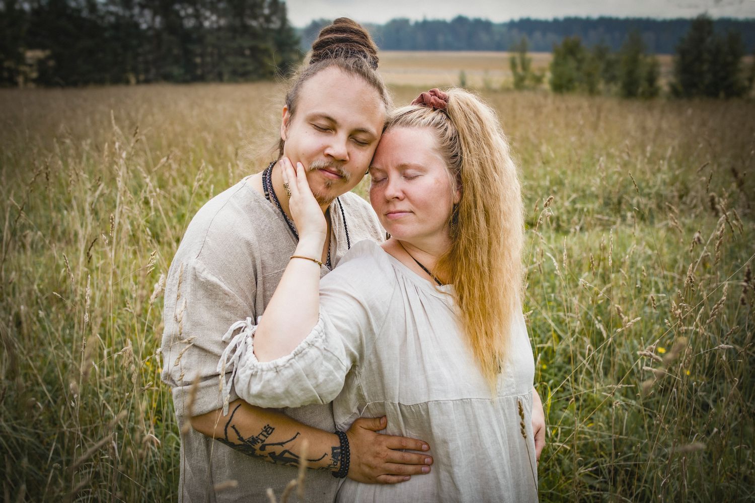Couple embracing tenderly in a golden field, wearing linen clothes, eyes closed in a peaceful romantic moment.