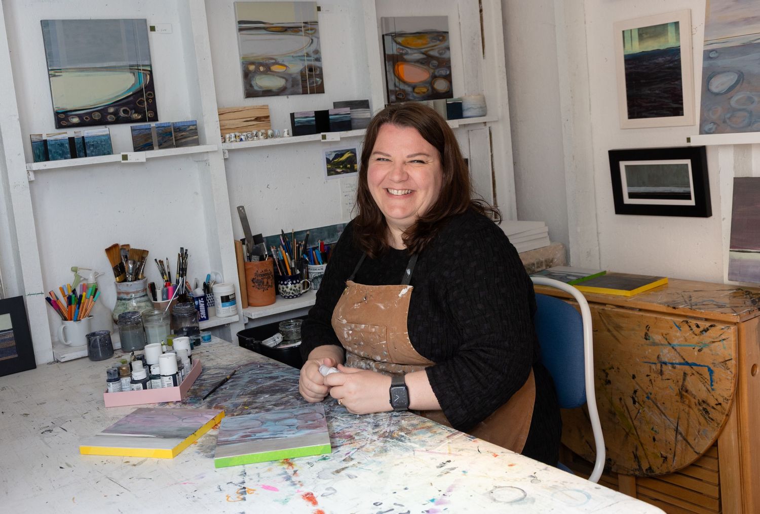 Female artist in her home studio surrounded by her artwork.