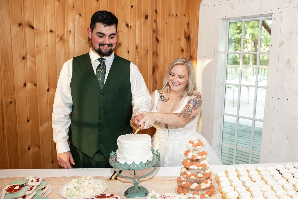 Bride and groom cutting their wedding cake together at a rustic barn reception venue.