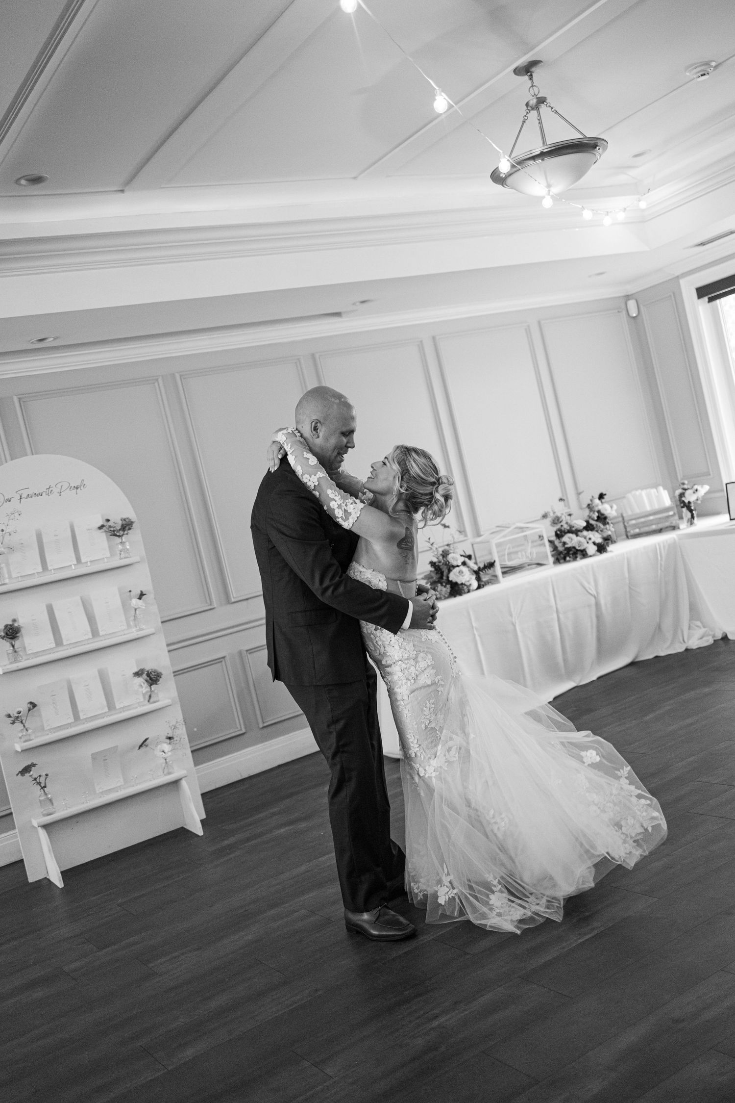 Black and white photo of bride and groom sharing their first dance at elegant wedding reception venue.