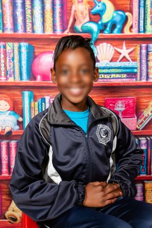 School portrait by Rynali Photography of a preschool learner smiling at the camera.