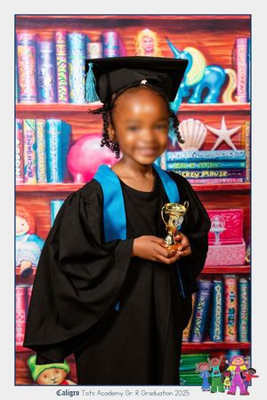 An image of school girl smiling at the camera for their Grade R graduation portrait, holding their graduation trophy.