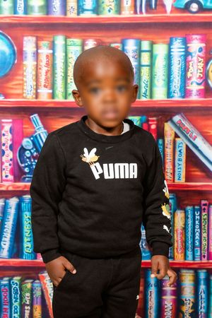 A picture of a pre-primary school learner posing for their preschool portrait.
