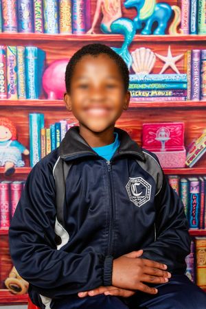 A picture of a primary school child smiling at the camera for their annual school portrait, in Pretoria, Gauteng.