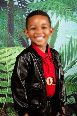 An image of a pre-primary school child, smiling at the camera for their preschool portrait.
