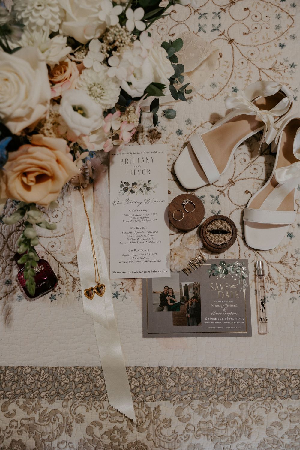 Elegant wedding flat lay with floral bouquet, invitation suite, rings, heels, and accessories on a decorative surface.