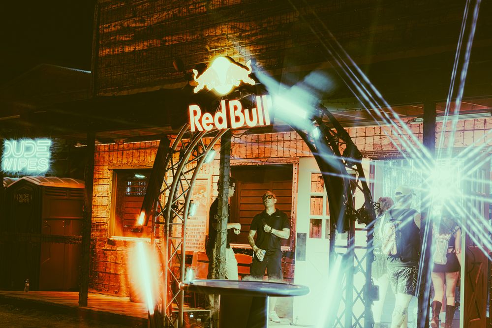 Red Bull branded stage setup with bright lights and performers at an indoor music or motorsport event.