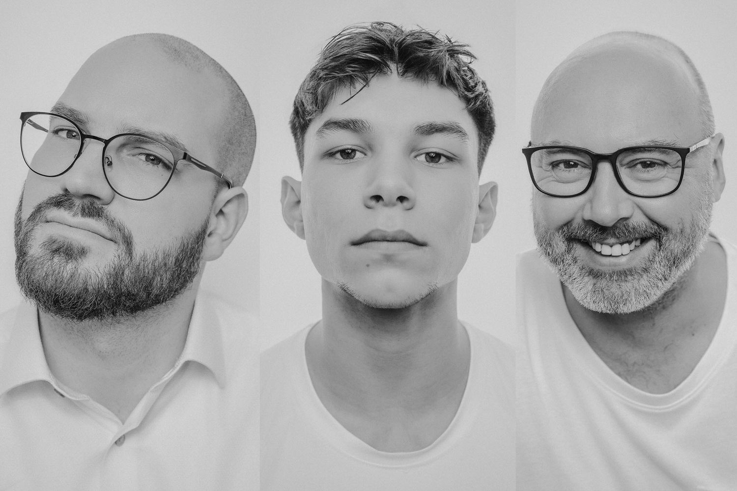 Black and white portrait of three men, two bald with glasses flanking a young man, against a white background.