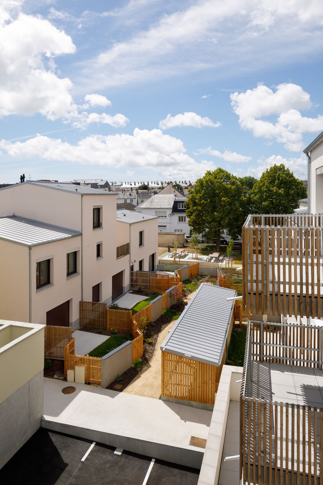 Vue aérienne d'un complexe résidentiel moderne avec des clôtures en bois, des jardins et des bâtiments beiges.