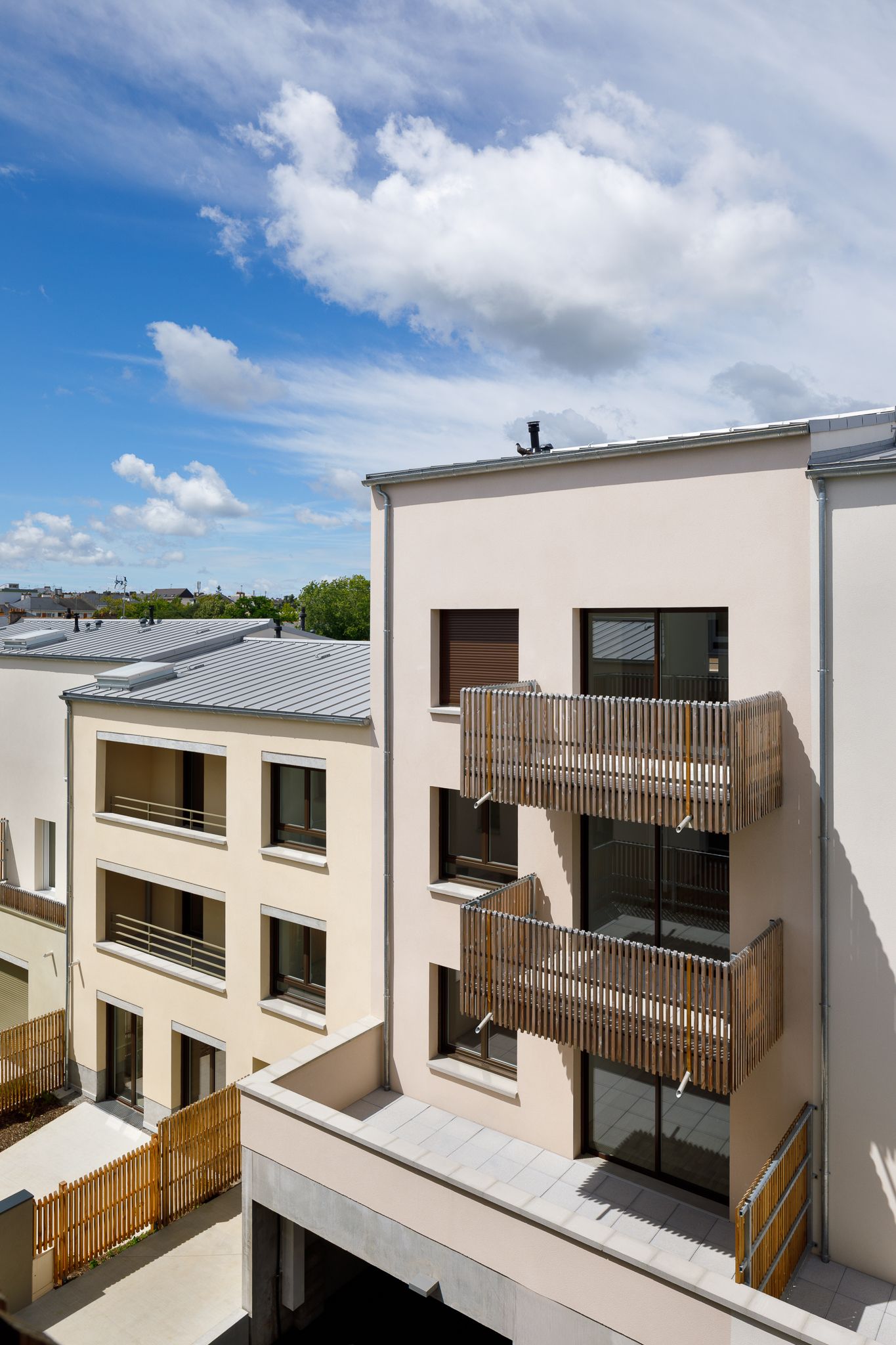 Immeuble d'appartements moderne de couleur beige, doté de balcons à lames de bois et de grandes fenêtres