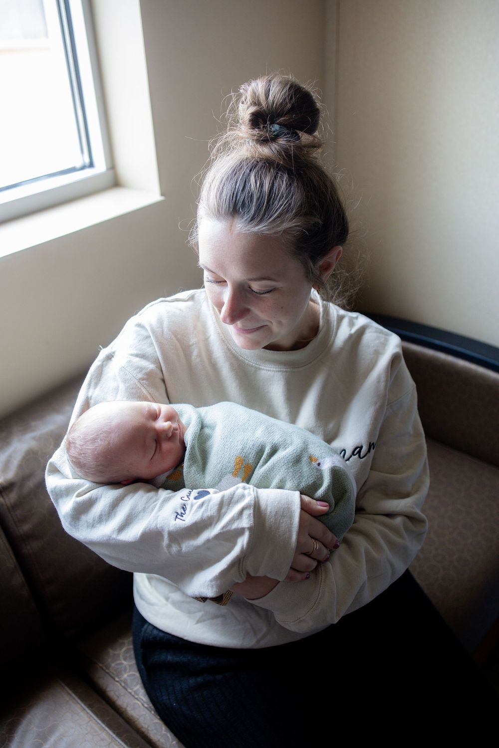 Mother and sleeping newborn baby cradled in her arms during fresh 48 session at the University of Tennessee with Nina Thomas Photography.