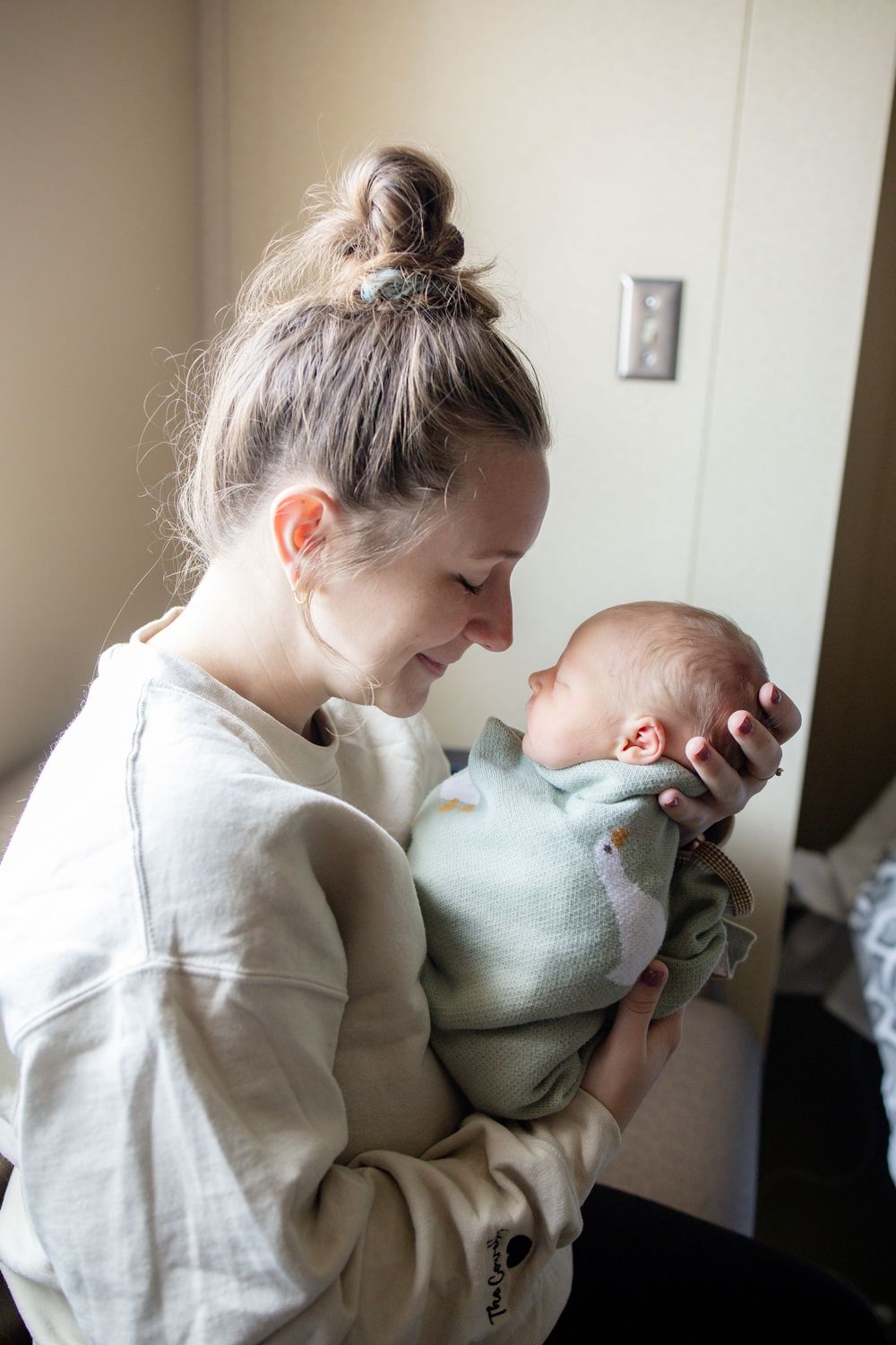 A smiling young mother with baby during fresh 48 session at the University of Tennessee with Nina Thomas Photography.