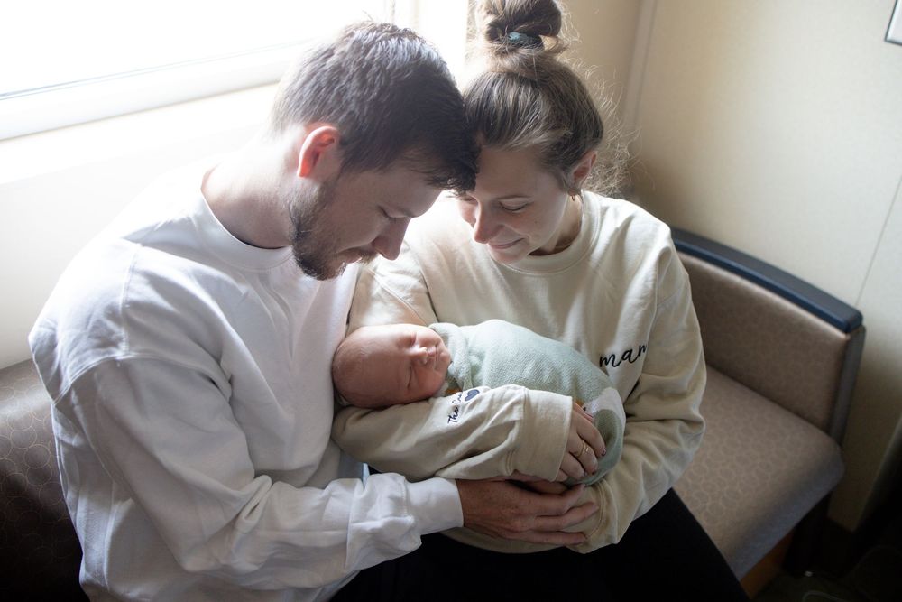 New parents tenderly cradling their newborn baby during fresh 48 session at the University of Tennessee with Nina Thomas Photography.