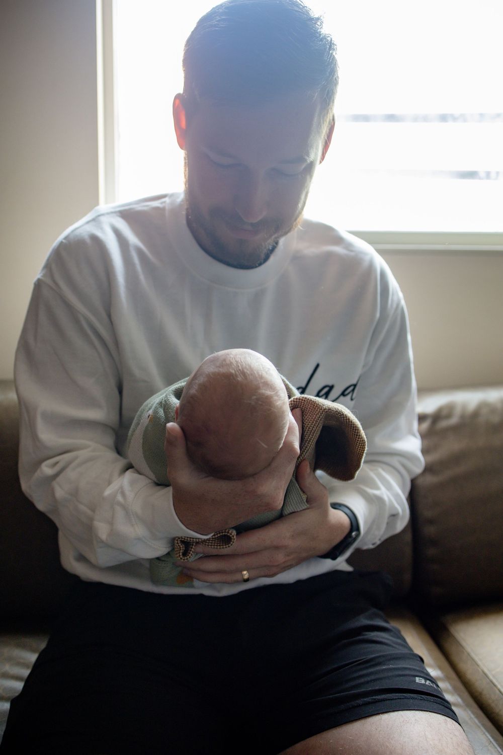 Father holding baby during fresh 48 session at the University of Tennessee with Nina Thomas Photography.