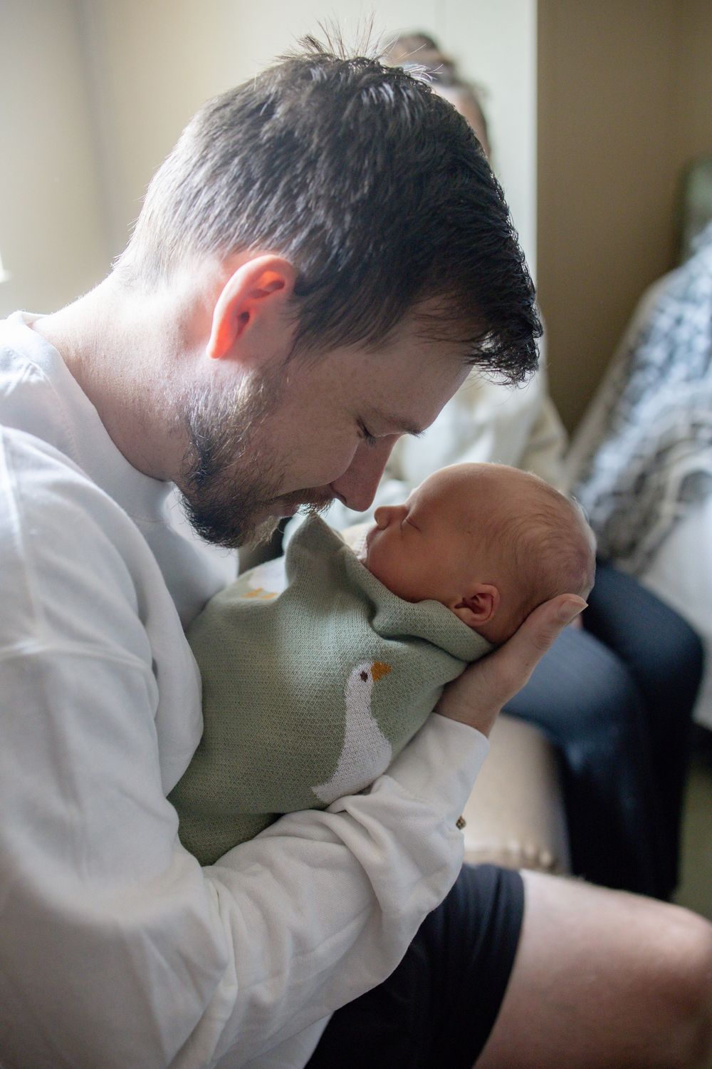 A bearded father tenderly holds his newborn baby during fresh 48 session at the University of Tennessee with Nina Thomas Photography.