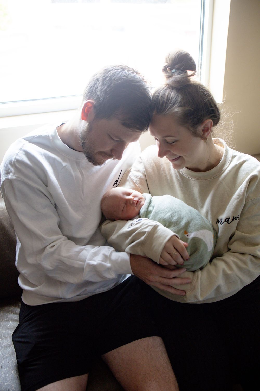 New parents tenderly cradle their sleeping newborn baby during fresh 48 session at the University of Tennessee with Nina Thomas Photography.