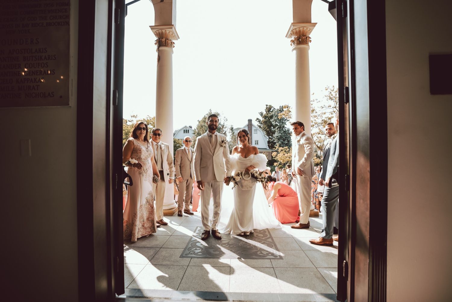 Bride and groom walking through church doors surrounded by wedding party in neutral tones.