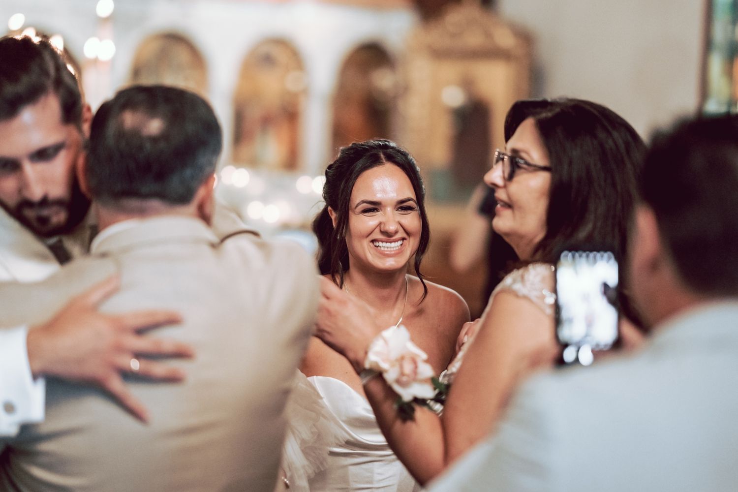 Bride laughing happily surrounded by family members during joyful wedding ceremony celebrations inside a church.