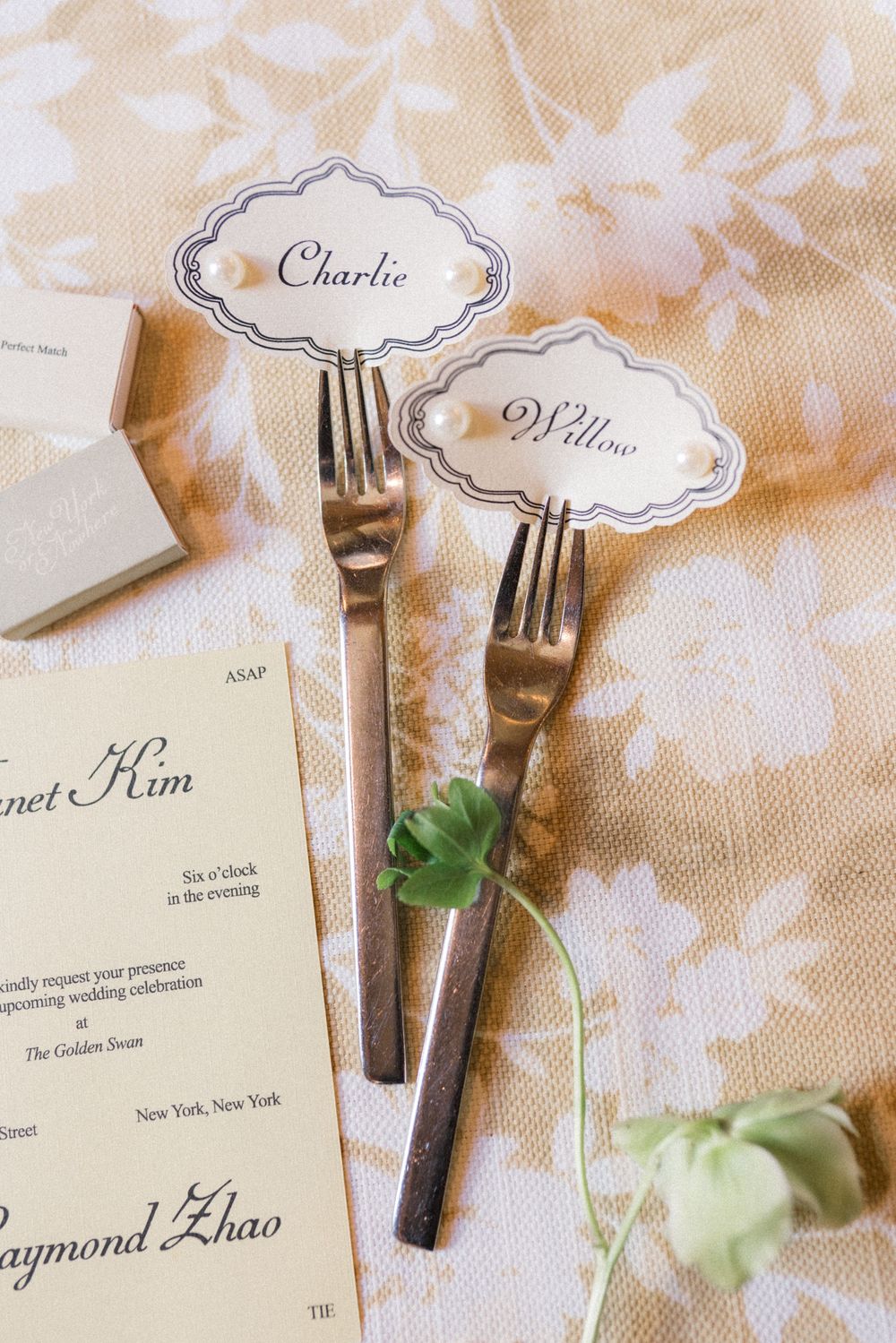 Vintage silver forks holding elegant place cards with names Charlie and Willow at a wedding reception table.