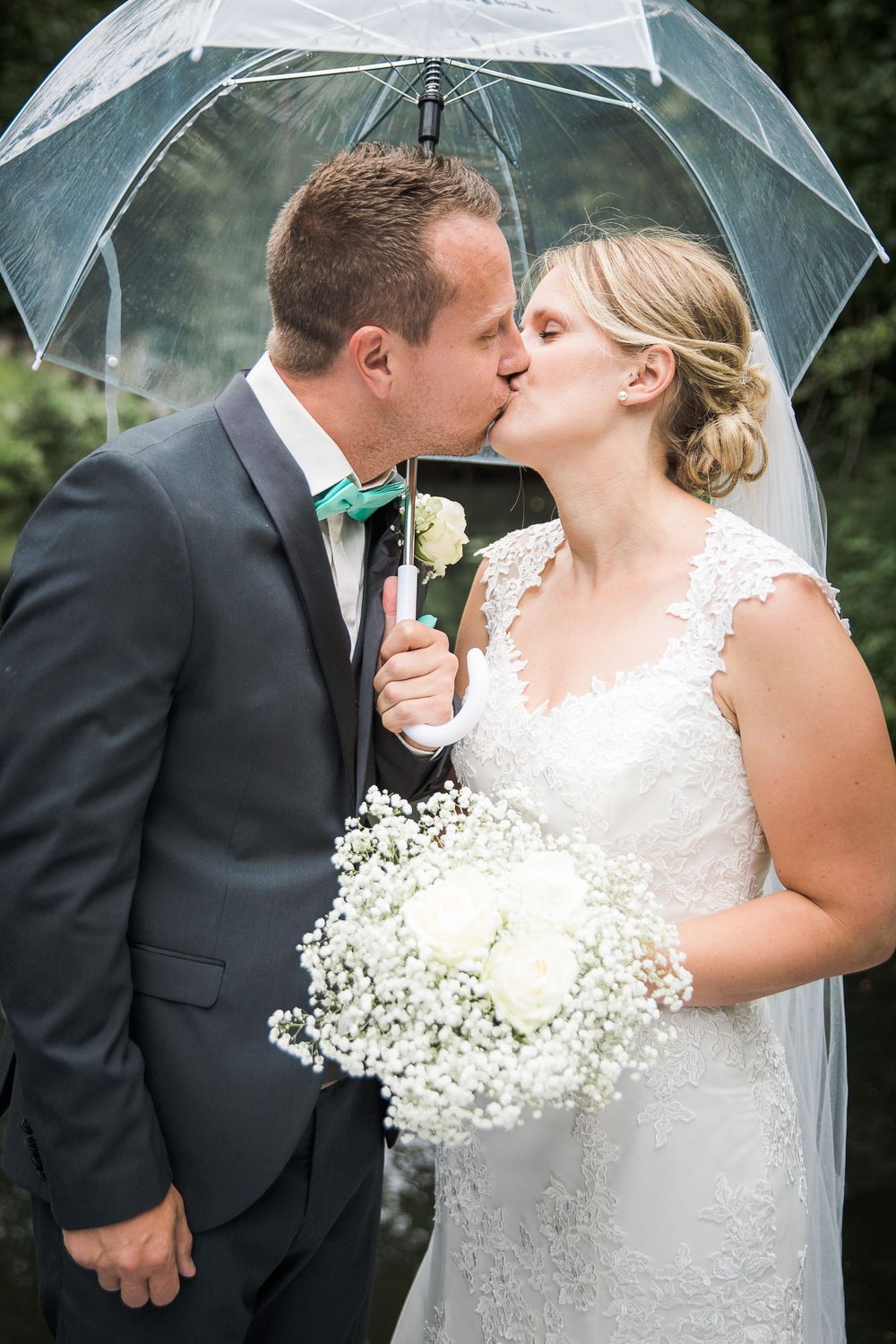 Brudepar kysser under en gennemsigtig paraply – bryllupsfoto af Martin & Louise