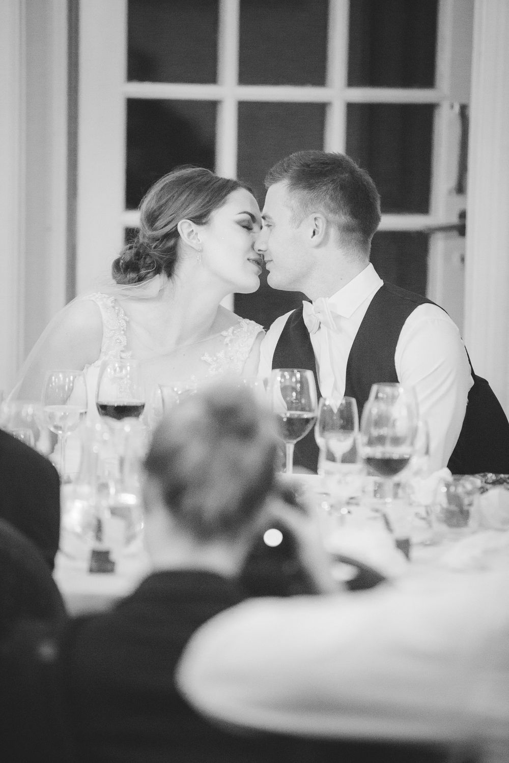 Brudepar kysser ved middagsbordet i sort/hvid – bryllupsfoto af Martin & Louise