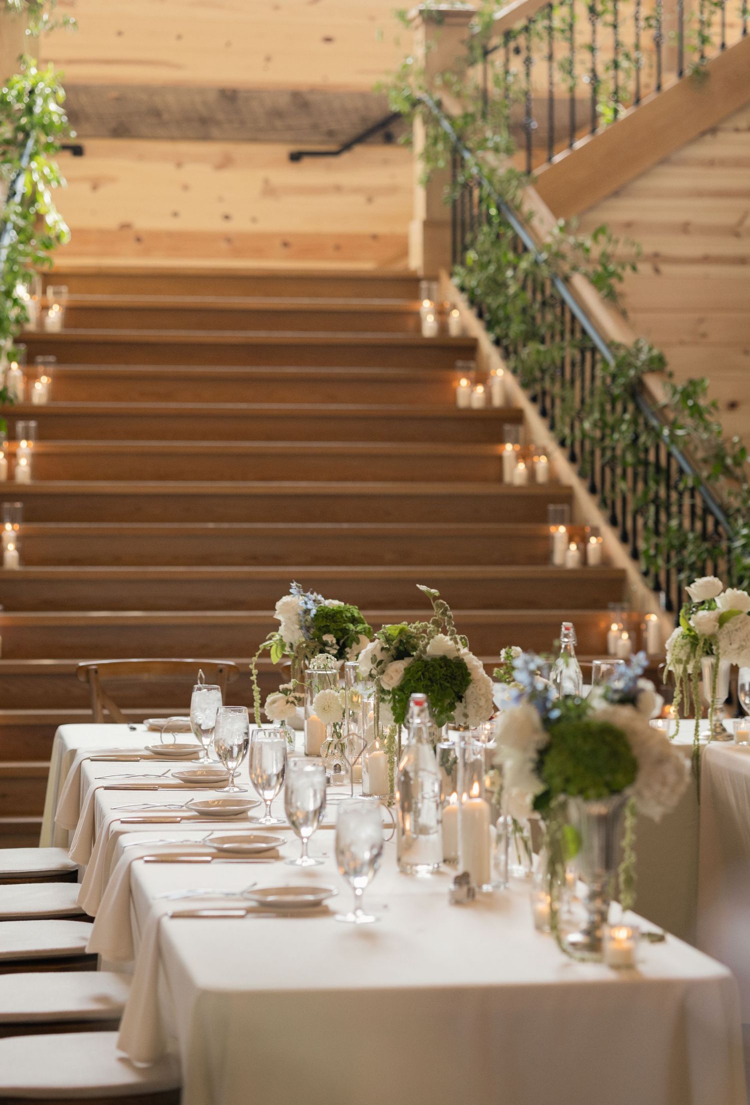 Candlelit reception tables with greenery centerpieces inside the barn at Tall Oaks Resort wedding in Sheffield Village, Ohio