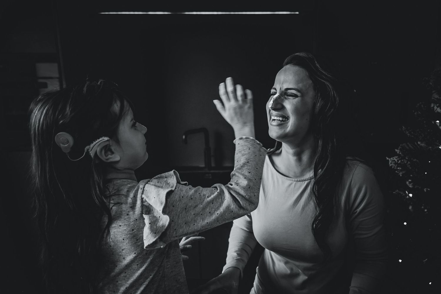 Photo of a smiling mom laughing as a daughter playfully touches her face with icing sugar during a storytelling baking photoshoot in Woerden