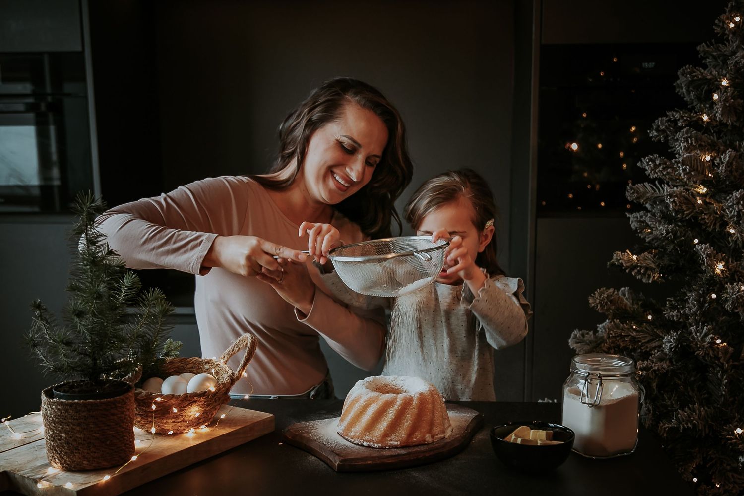 Mother laughing with her daughter while decorating a cake during a storytelling family baking photoshoot in the Netherlands.