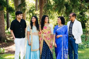 A photo of a family of 5 looking at each other, the women dressed nicely in Indian sarees