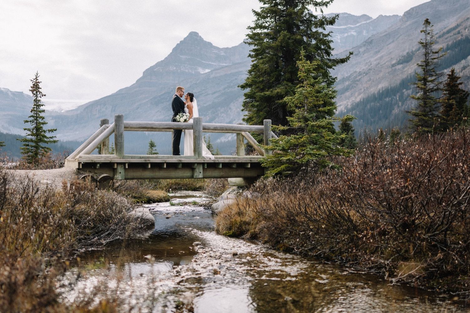 Couple on a wooden footbridge over a creek near Lake Louise