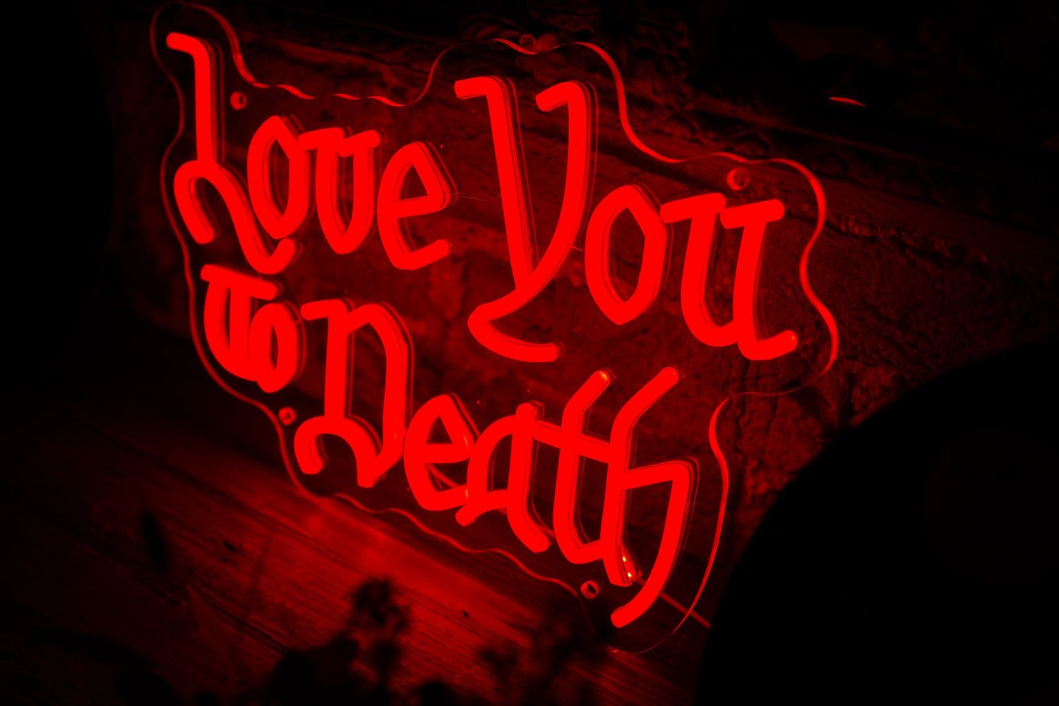 Red neon sign reading Love You to Death at a Halloween themed wedding