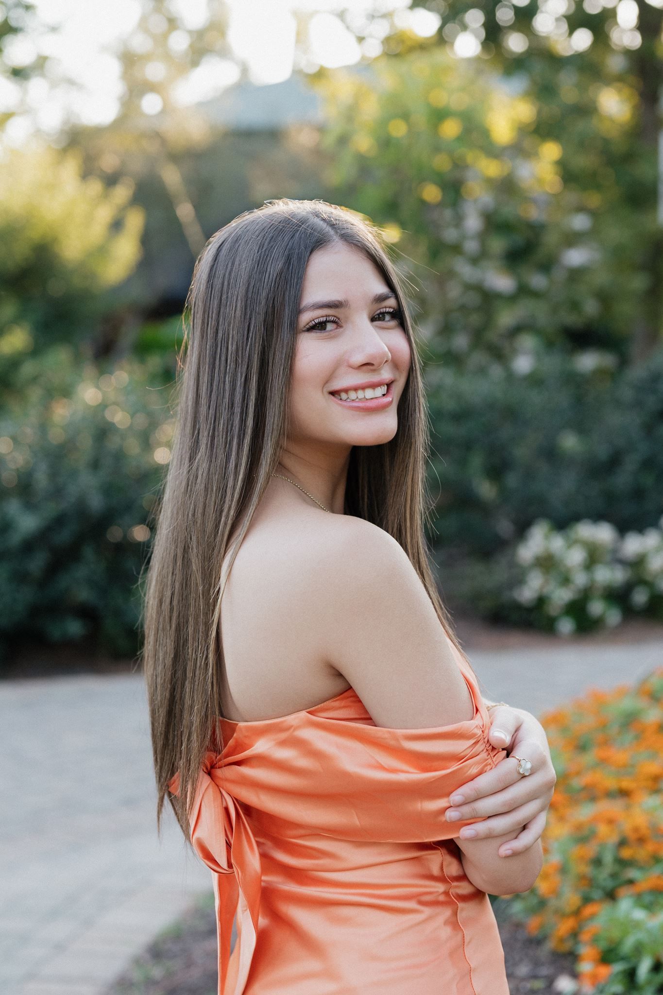 College Park High School senior girl, wearing short orange dress, at Mercer Botanic Garden in Spring Texas.