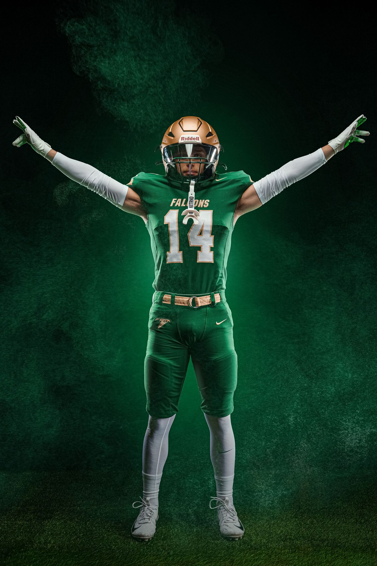 Football player #14 in green and gold Falcons uniform poses with arms raised against a dramatic dark green smoky background.