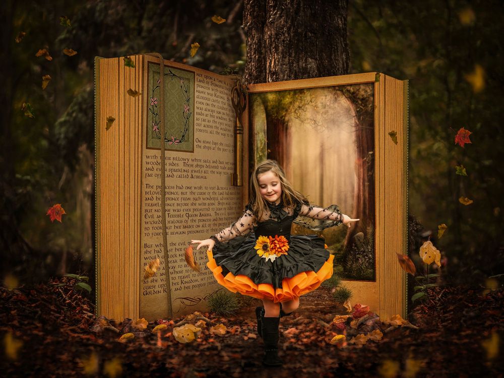 a little girl dressed as a witch standing in front of a large storybook book