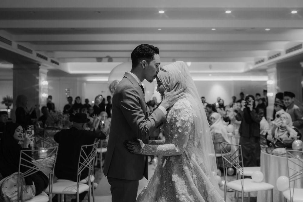Black and white photo of a couple sharing a romantic moment at their wedding reception in an elegant venue.