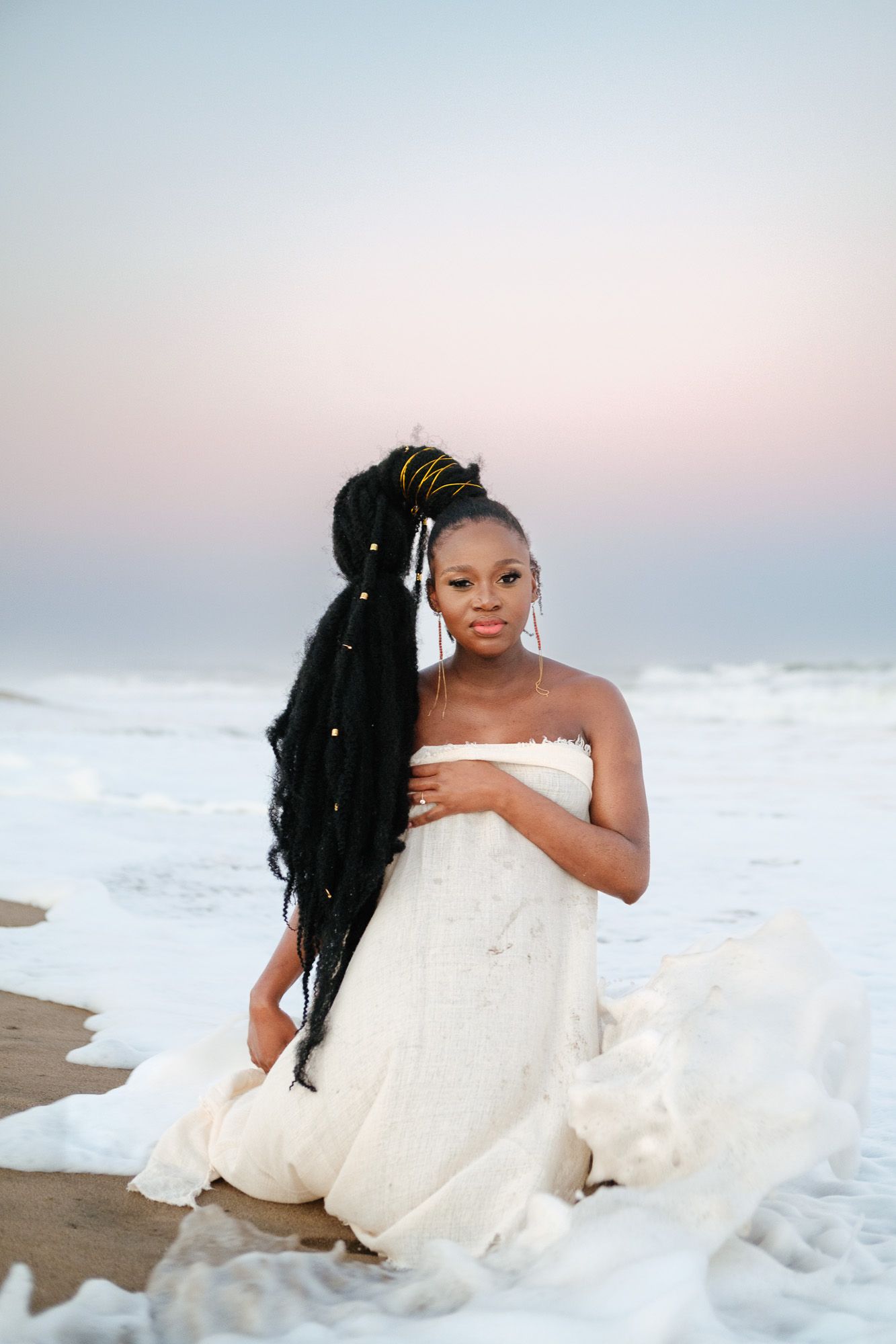Elegant portrait of pregnant mom kneeling in the waves at Mtunzini beach