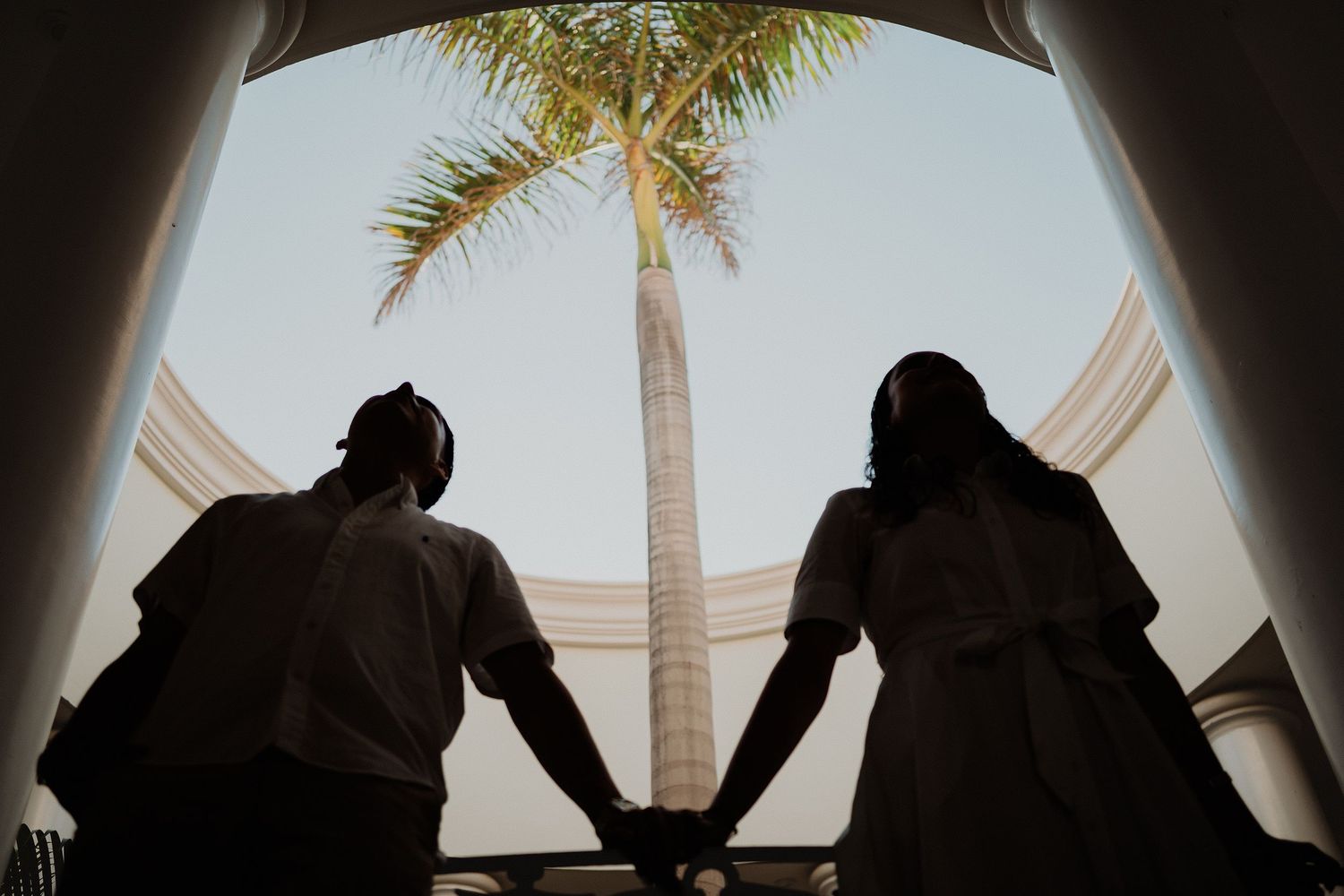 Fotografía espontánea de pareja entre palmeras en Mazatlán.