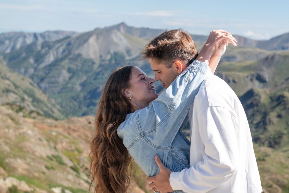 Bride and groom sharing a kiss on a mountain summit with stunning alpine scenery behind them.