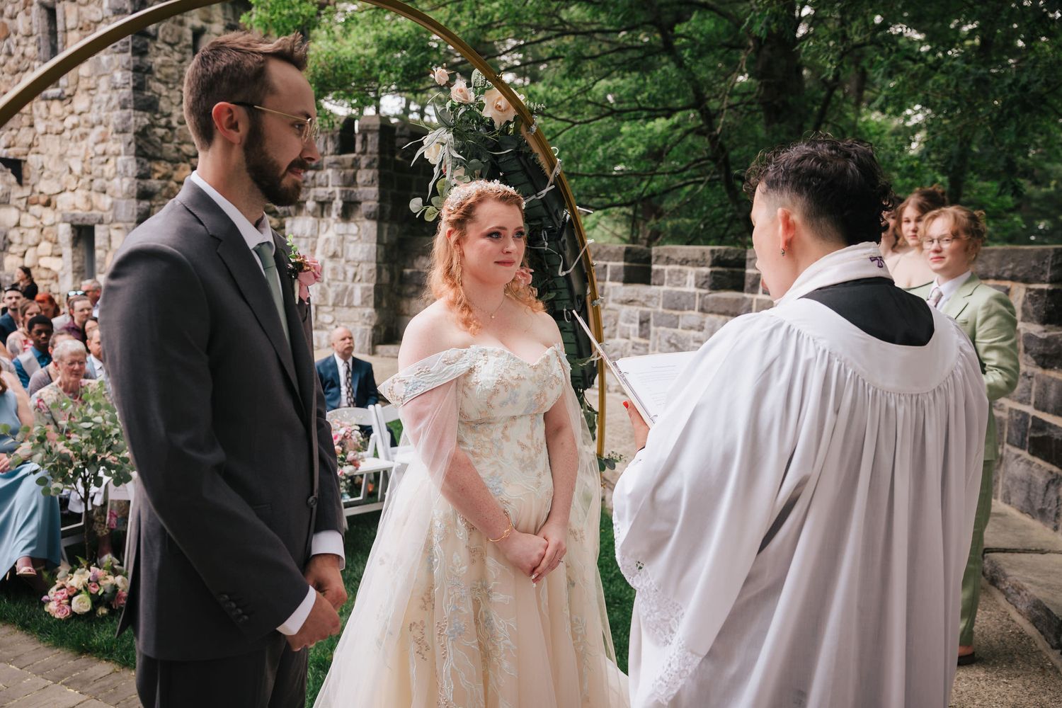 Bride and groom facing the officiant during their vows, bride visibly emotional, at Searles Castle.