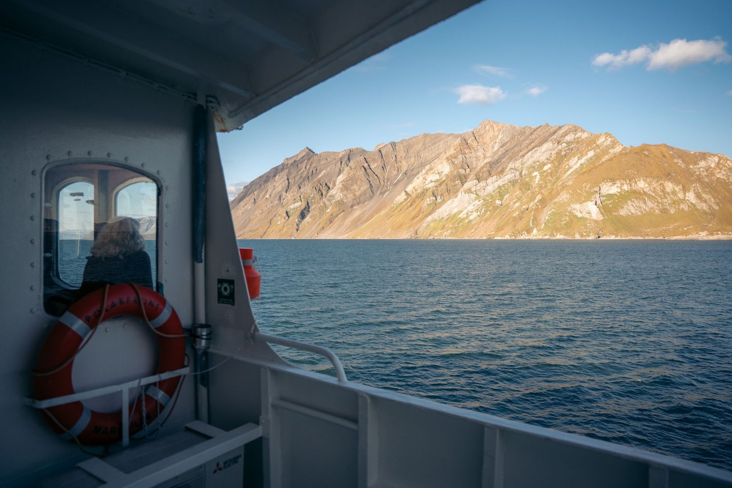 Passagère au poste de veille dans une coursive du Polarfront, montagne dorée en fond