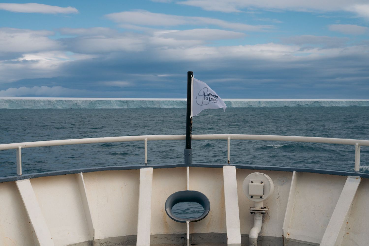 brasvellbreen.jpg	Fanion de la croisière Latitude Blanche à la proue face à la barrière de Bråsvellbreen