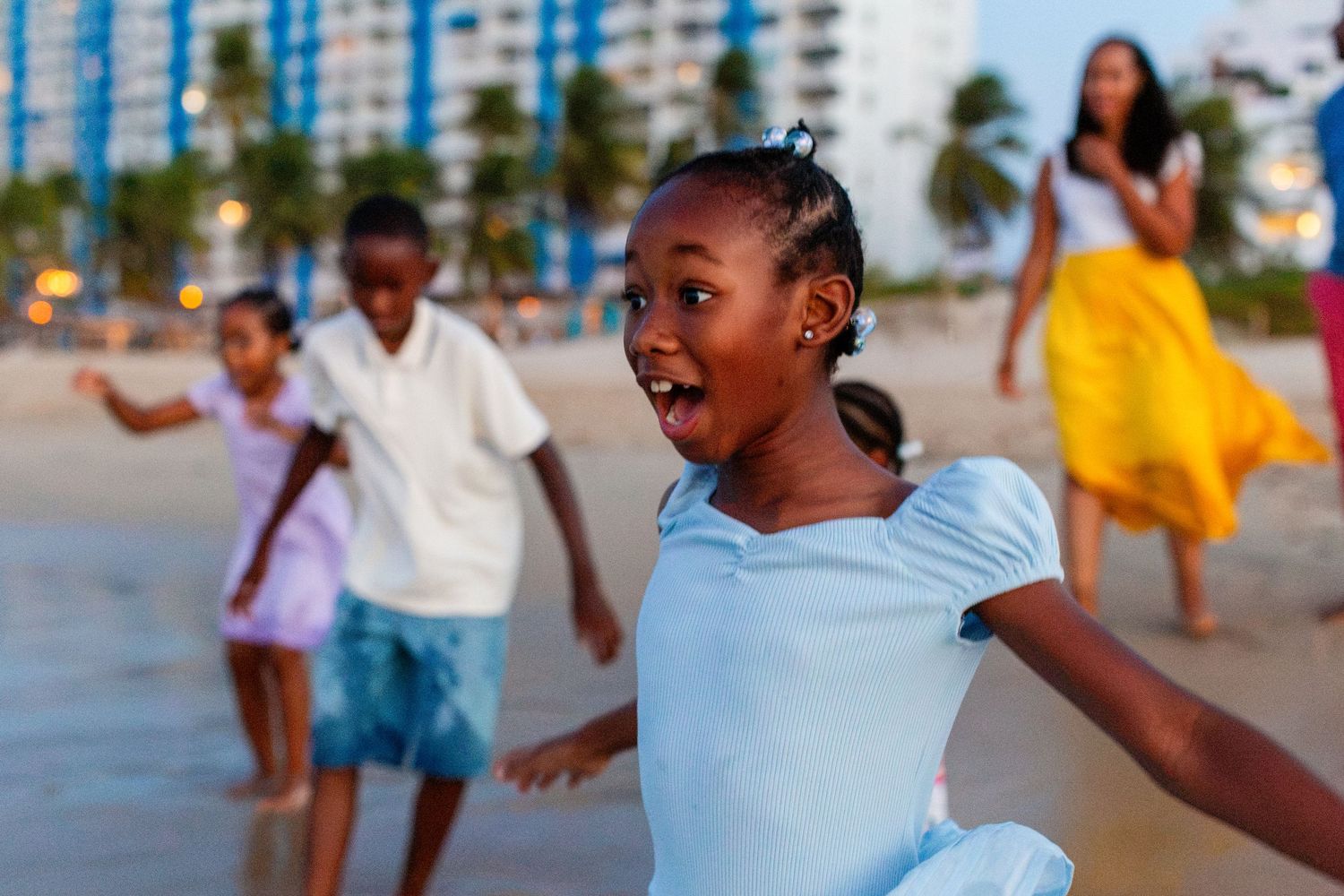 A very excited little girl and her family in the background on the beach in Isla Verde, Carolina, Puerto Rico.