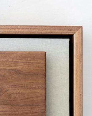 Close-up of a wooden picture frame with walnut finish, showcasing layered matting and fine craftsmanship detail.