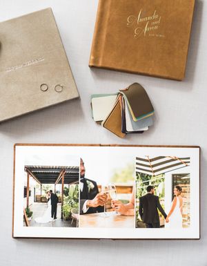 Open wedding photo album with bride and groom images, beside a gold personalized keepsake box and color swatch samples.