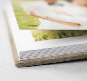 Close-up of a hardcover photo book with linen spine and glossy printed pages featuring an outdoor portrait.