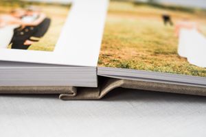 Close-up of a thick wedding photo album with a gray fabric cover, showcasing printed photos inside.