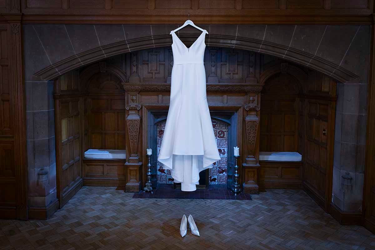 Wedding dress hanging in the grand fireplace at Dalston Hall wedding venue