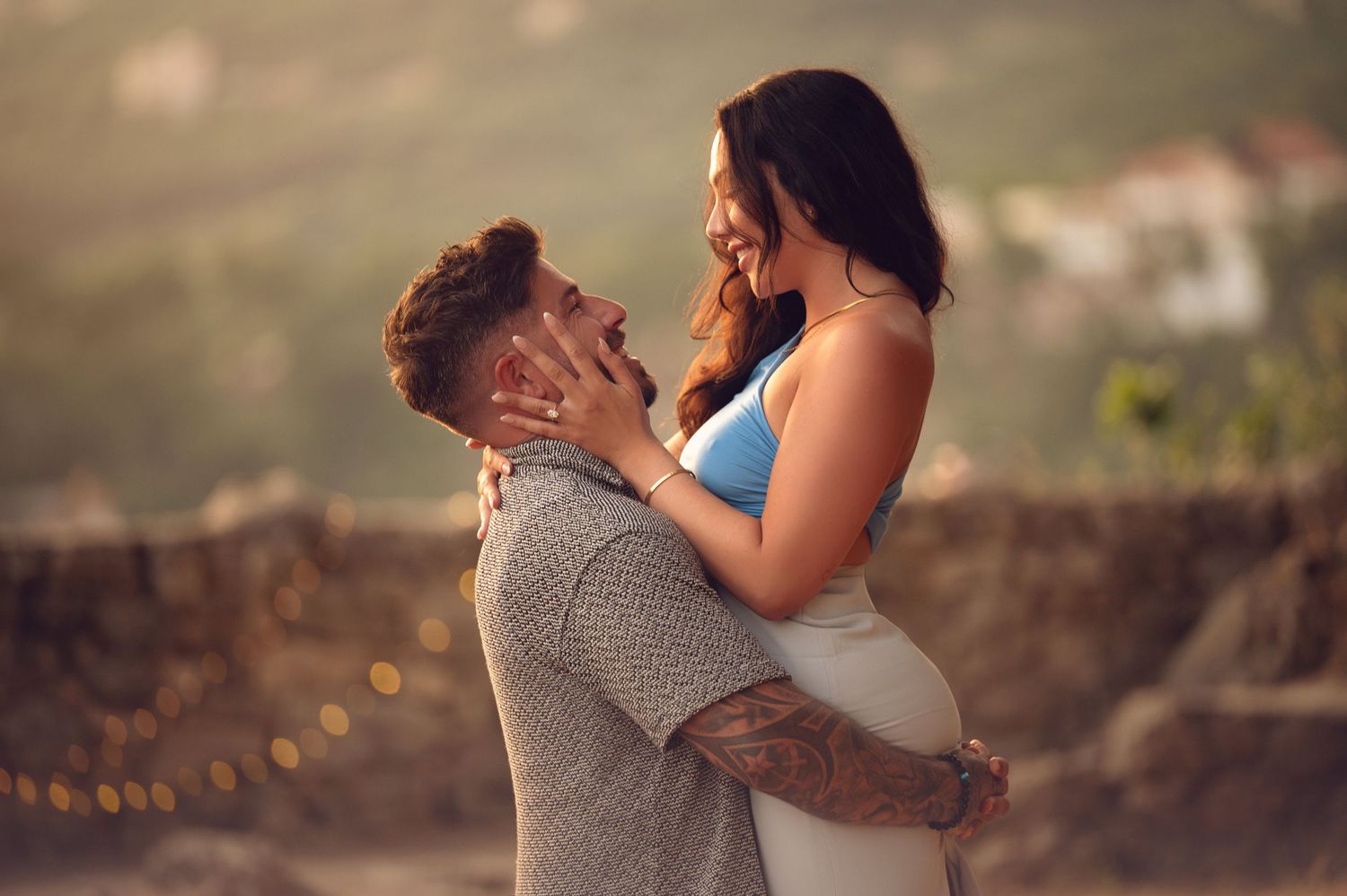 Man proposing on one knee to woman at sunset with mountain backdrop in a romantic outdoor setting.